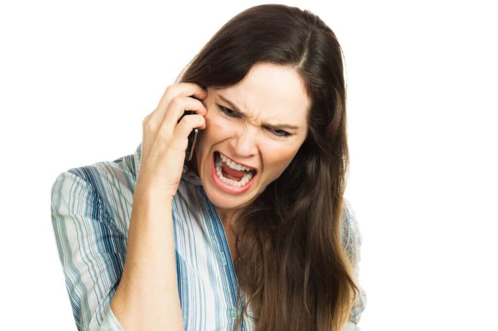 An angry and very frustrated business woman yelling on the phone. Isolated over white.