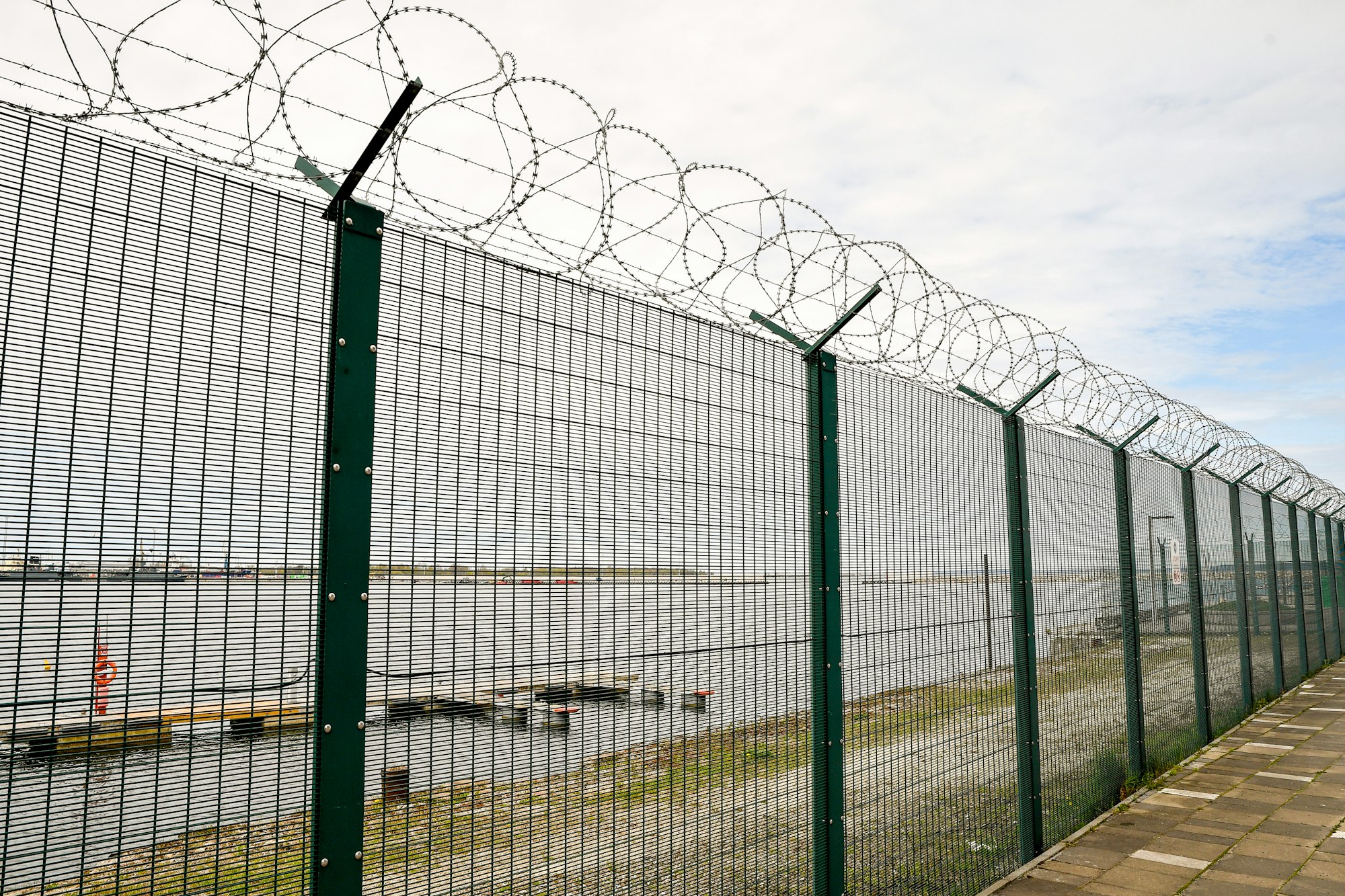 Security fence with razor wire around an industrial site, the kind of perimeter covered by CIRMP physical security requirements